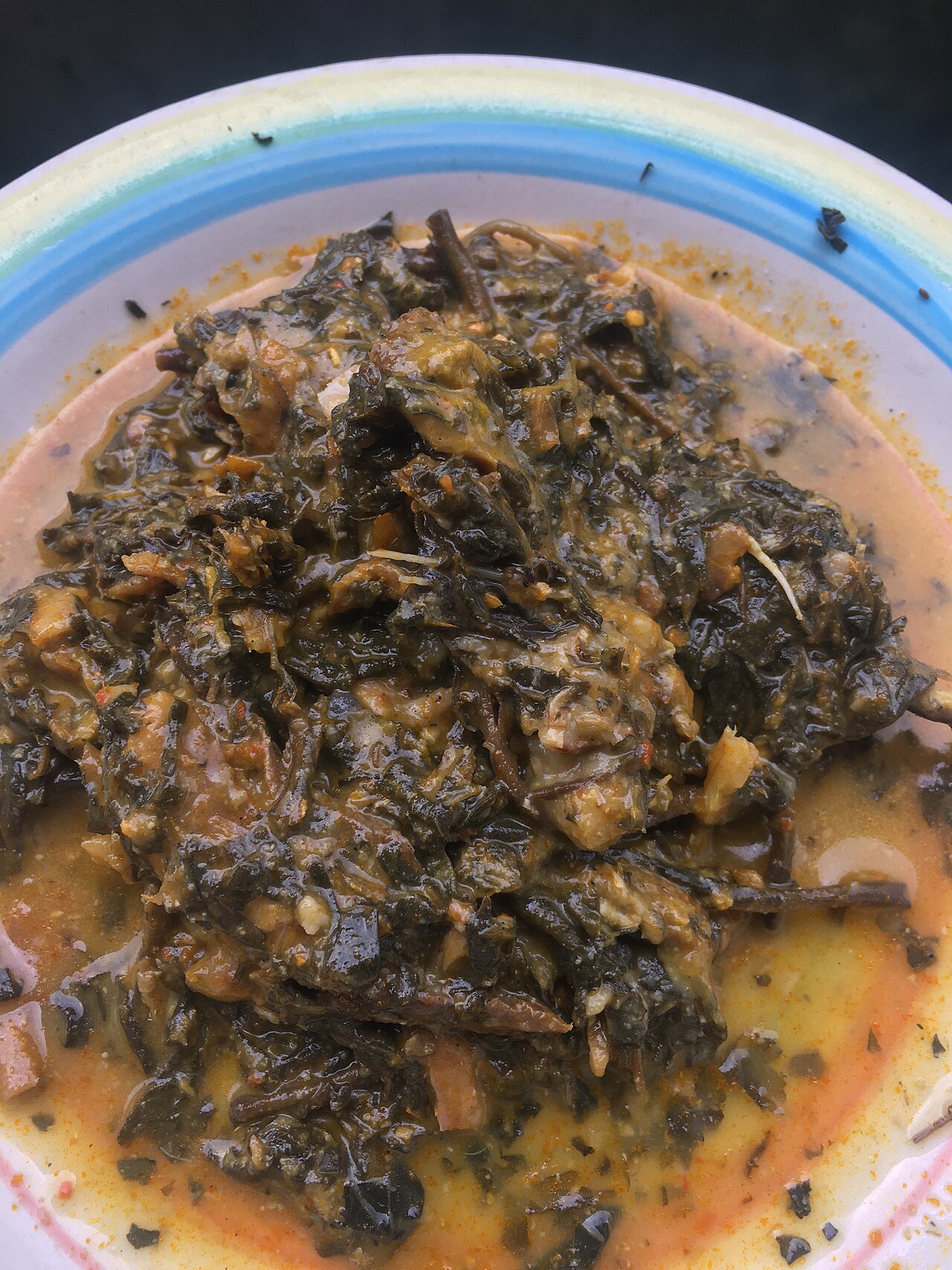 A bowl of cooked Nigerian rice and boiled eggs on a wooden kitchen table.